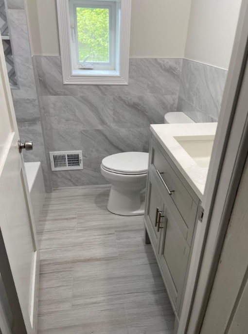 Gray vanity with a light countertop beside coordinated wall tile