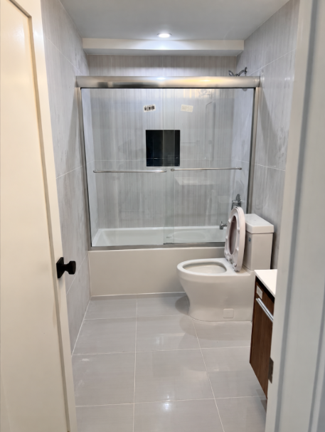 Bathtub with sliding glass doors and tiled surround