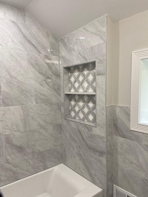 Close-up of gray tile with a two-tier recessed niche finished in diamond-pattern tile